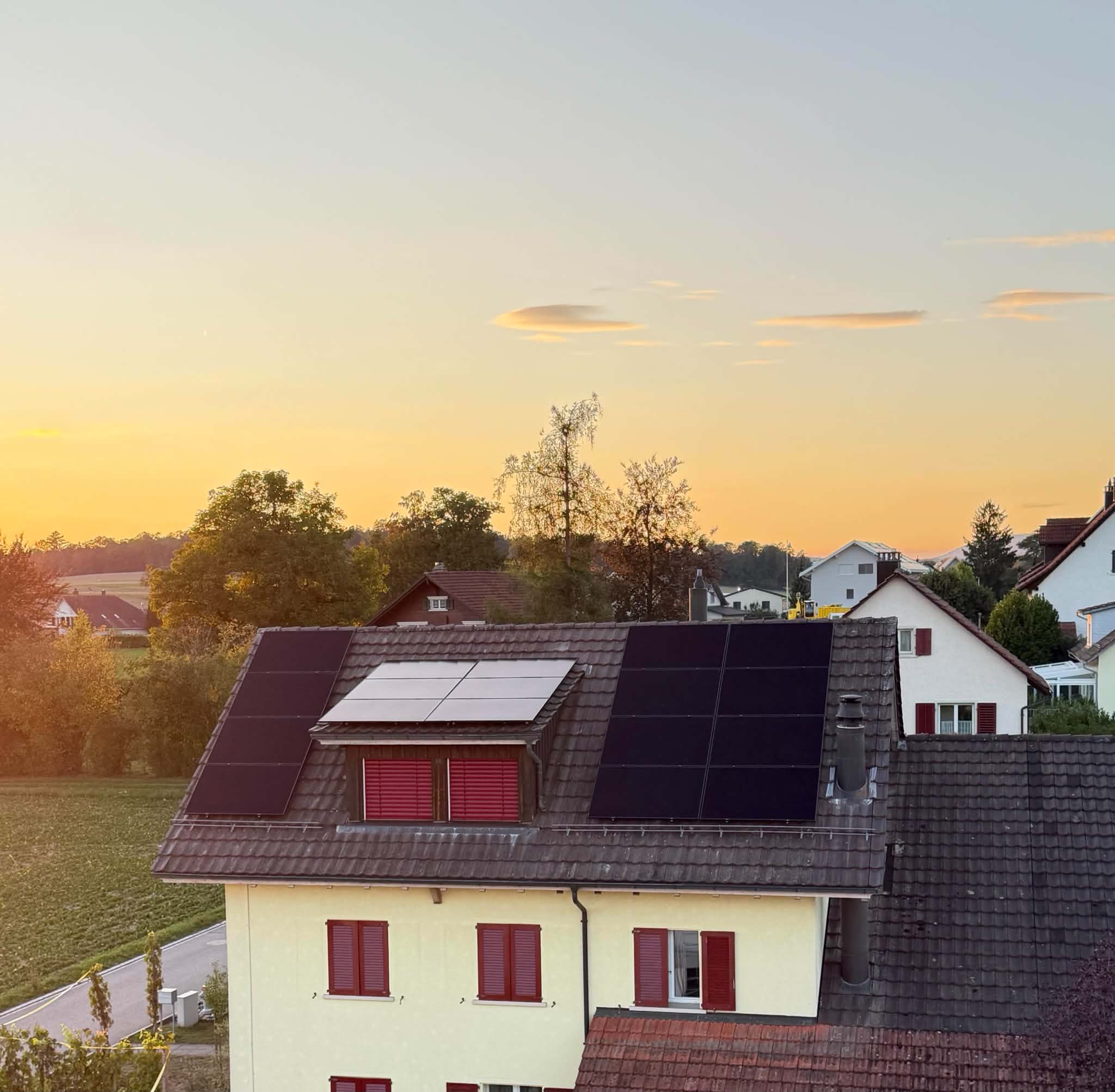 Solarmodule um eine Dachgaube auf einem Einfamilienhaus im Sonnenuntergang