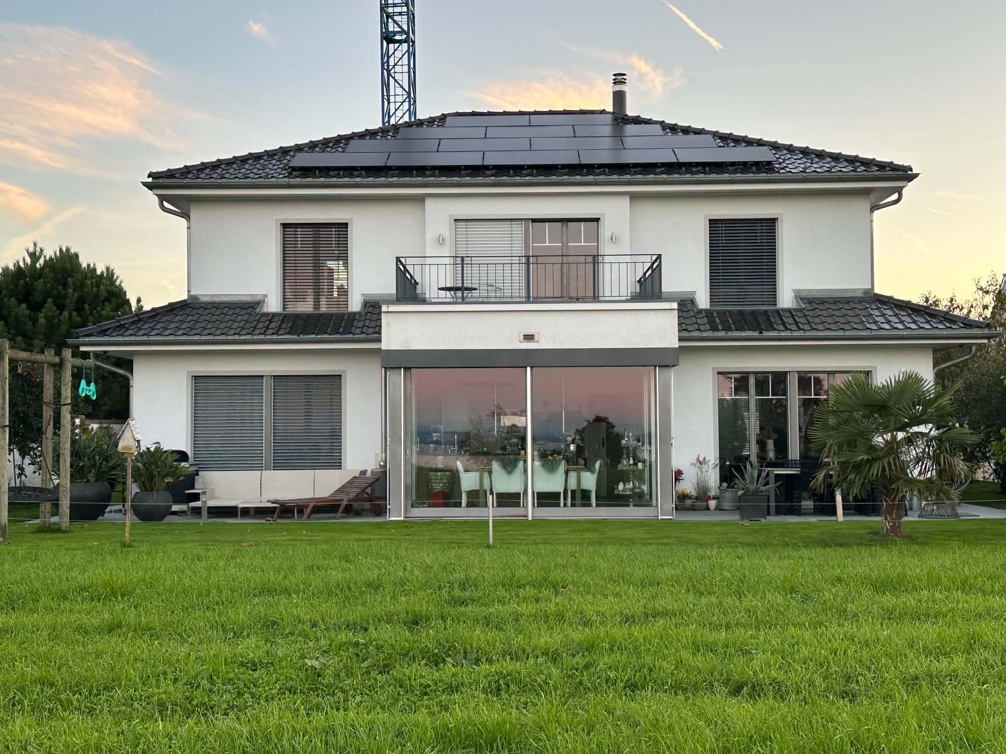 Weisses Einfamilienhaus mit Solardach, vom Garten aus gesehen